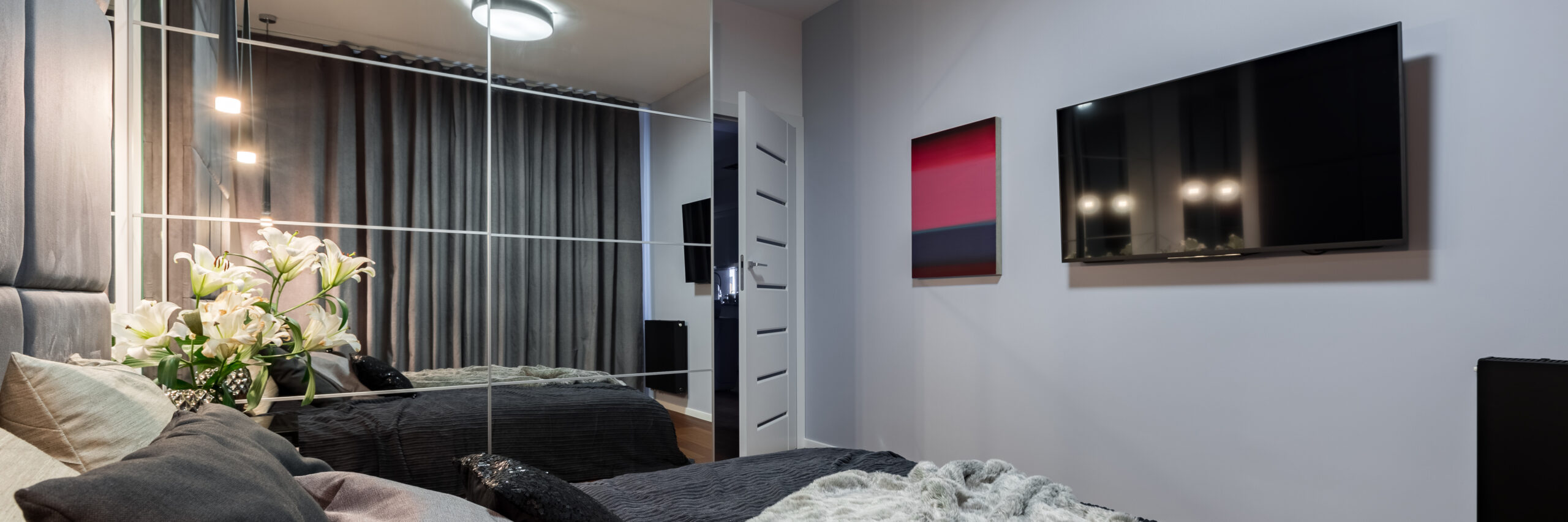 Elegant bedroom with double bed, mirrored wardrobe and tv, panorama